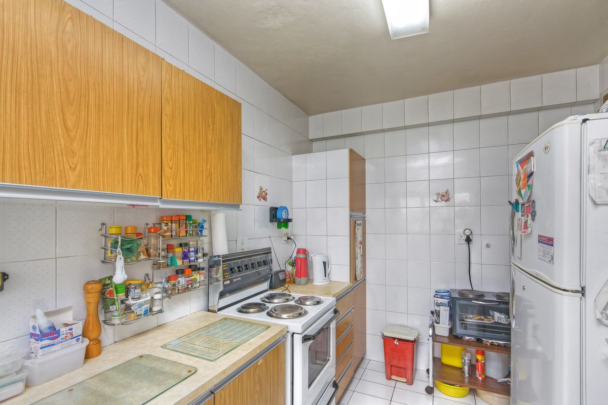 A functional kitchen featuring wood-look cabinetry, tiled walls, and a built-in electric stove, offering a practical layout for daily meal preparation.