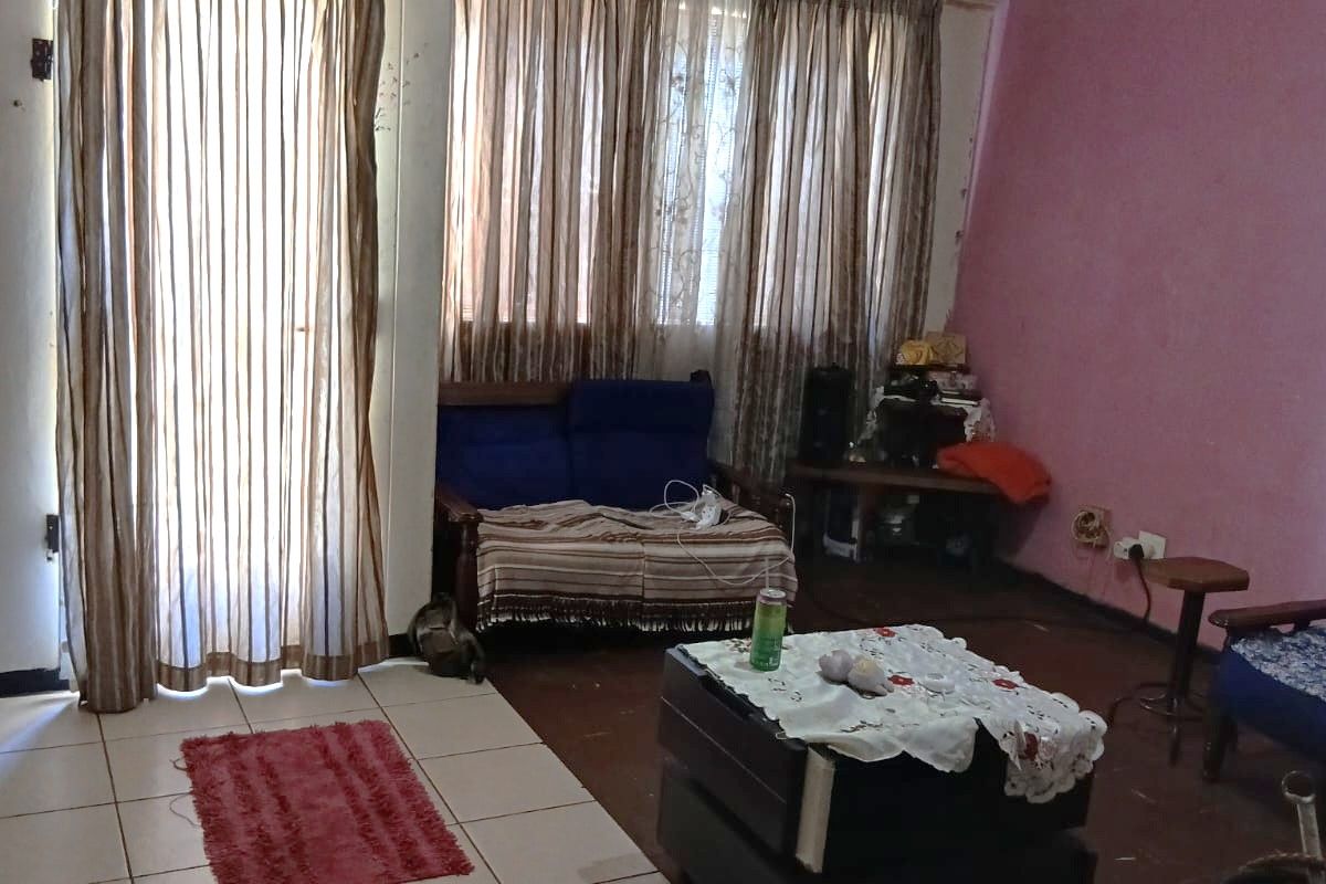 A living room area featuring tiled flooring, large windows with curtains, and a transition to a secondary floor surface.