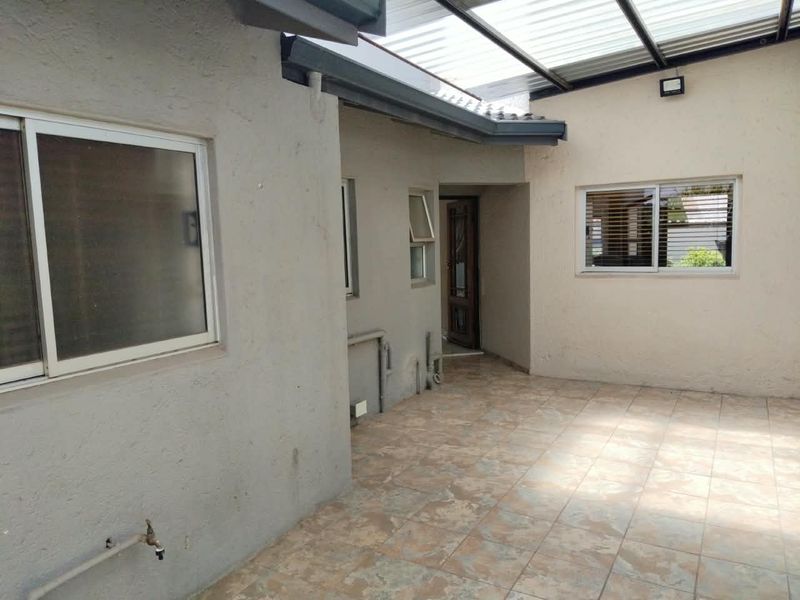 A covered outdoor patio area featuring tiled flooring, a translucent roof, and direct access to the home's exterior.