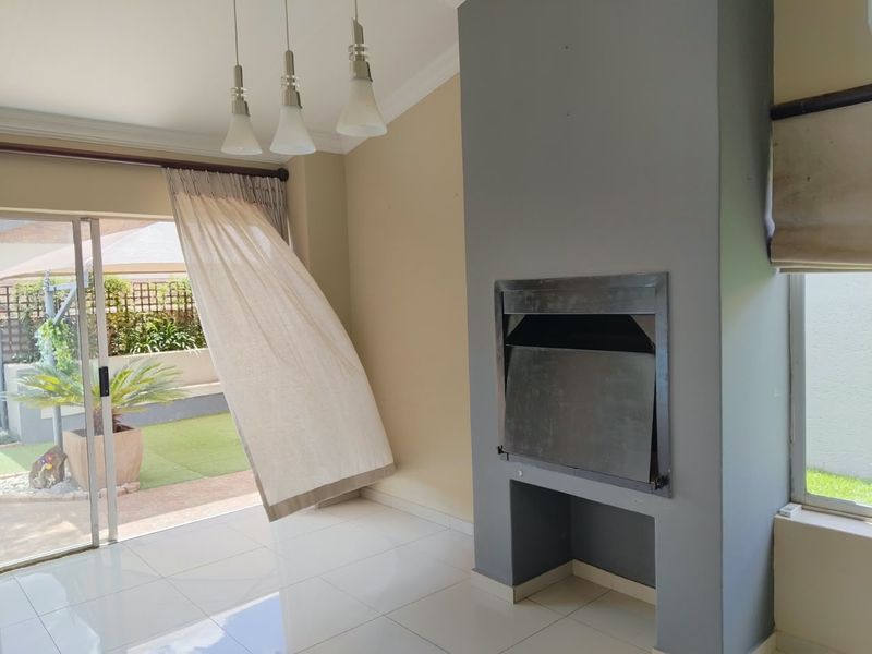 Bright living area featuring a modern built-in fireplace, sleek tiled flooring, and large sliding doors providing seamless access to the outdoor patio and garden.