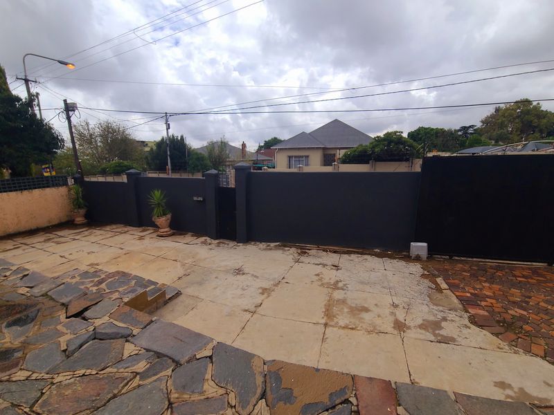 Front exterior area featuring a paved driveway, boundary wall, and sliding gate access.