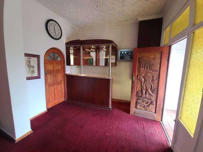 A dedicated bar area featuring a built-in wooden counter, display shelving, and unique carved wooden doors, offering potential for a modern entertainment space.