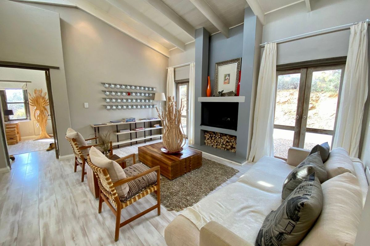 Spacious living room featuring high vaulted ceilings with exposed beams, a central fireplace with integrated wood storage, and large glass doors leading outdoors.