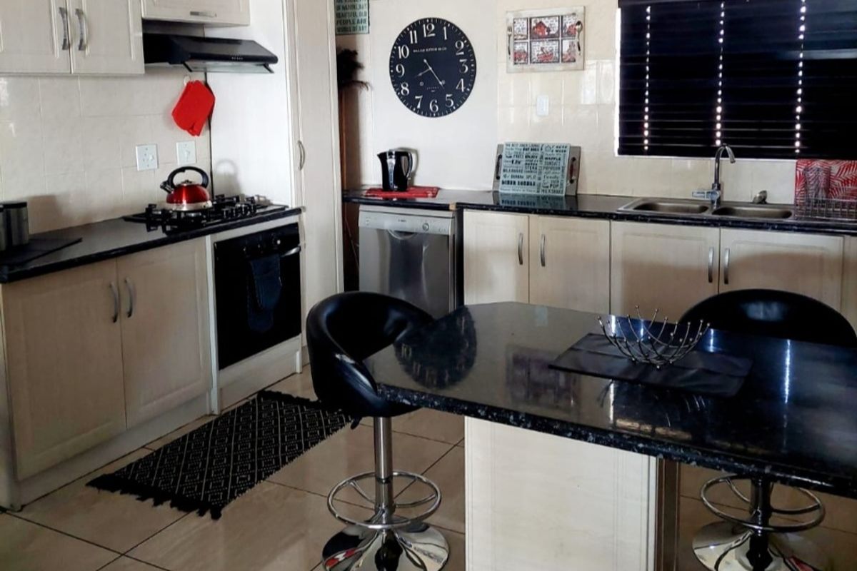 A functional kitchen featuring granite countertops, built-in cabinetry, a gas hob, an under-counter oven, and a central breakfast island with seating.