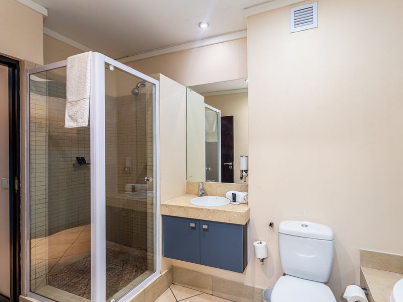 A functional bathroom featuring a glass-enclosed shower, a vanity with stone countertop, and a standard toilet, presenting a clean and practical layout.