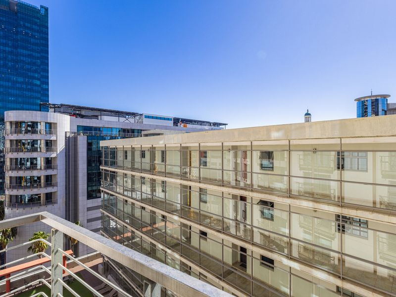 An elevated urban view from a balcony overlooking surrounding high-rise apartment buildings and city architecture.