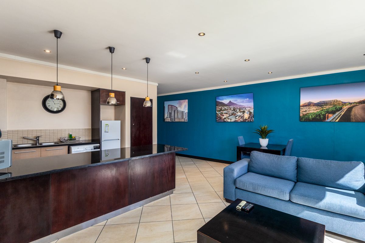 Open-plan living area featuring a kitchen with a granite island, tiled flooring, and recessed lighting, seamlessly flowing into the lounge and dining space.