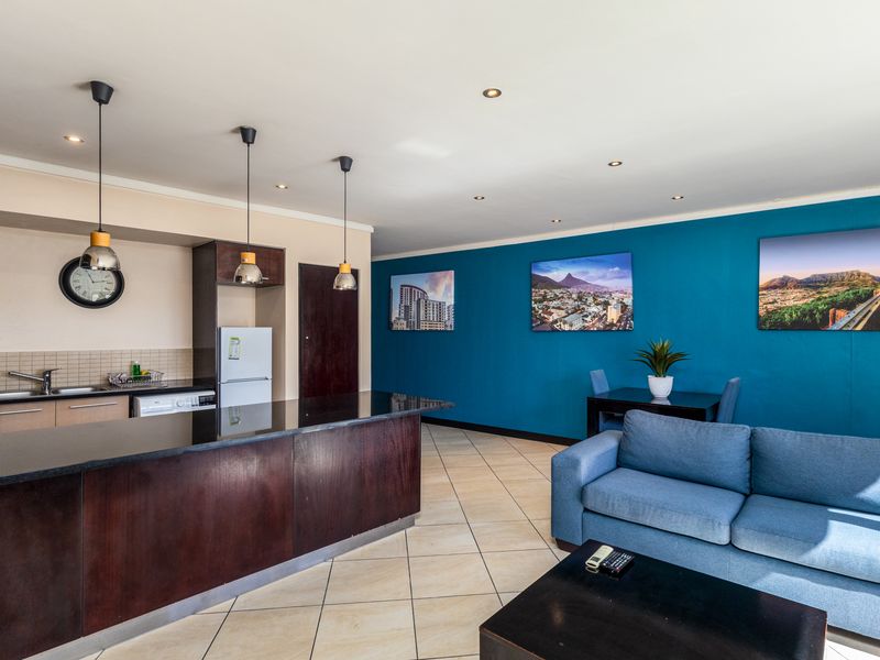 Open-plan living area featuring a kitchen with a granite island, tiled flooring, and recessed lighting, seamlessly flowing into the lounge and dining space.