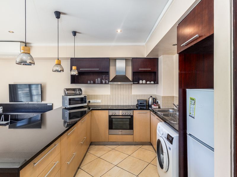 Open-plan kitchen featuring modern cabinetry, granite countertops, integrated appliances, and a breakfast bar, seamlessly flowing into the living area.