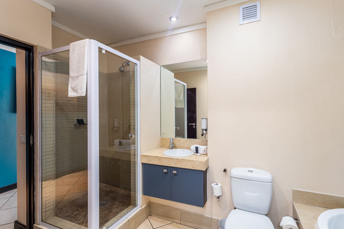 A functional bathroom featuring a glass-enclosed shower, a vanity with stone countertop, and a standard toilet, presenting a clean and practical layout.