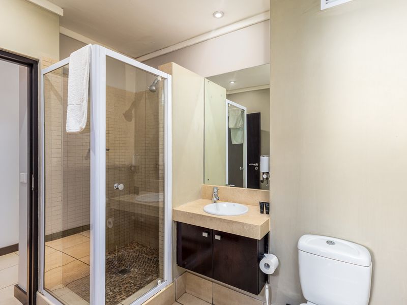 A functional bathroom featuring a glass-enclosed shower, a vanity with a stone countertop, and a standard toilet.