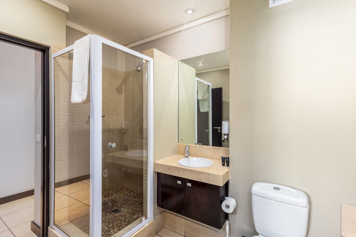 A functional bathroom featuring a glass-enclosed shower, a vanity with a stone countertop, and a standard toilet.