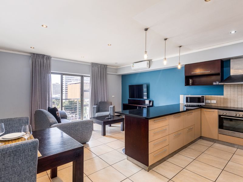 Modern open-plan living area featuring a well-equipped kitchen with granite countertops, built-in appliances, and seamless flow to the balcony.