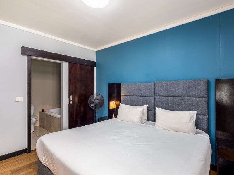 A well-maintained bedroom featuring laminate flooring, a bold blue accent wall, and a convenient sliding door leading to an en-suite bathroom.