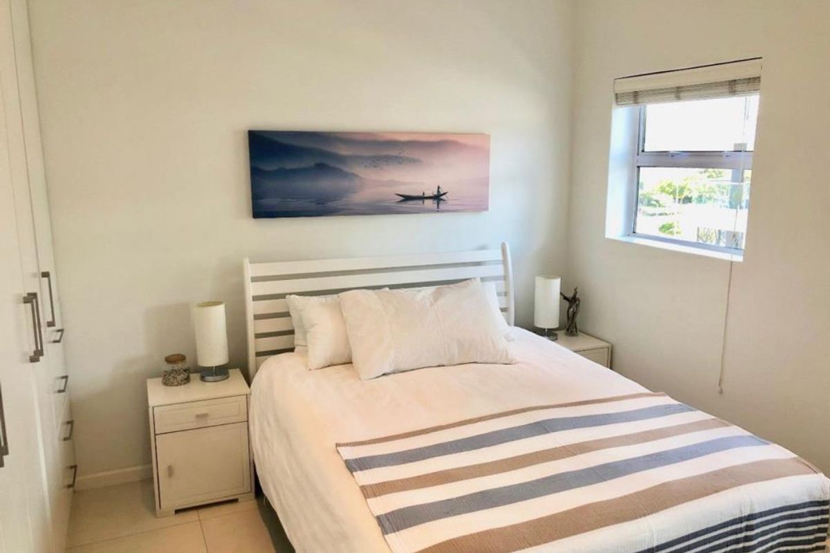 A well-maintained bedroom featuring built-in cupboards, tiled flooring, and a window with a roller blind.