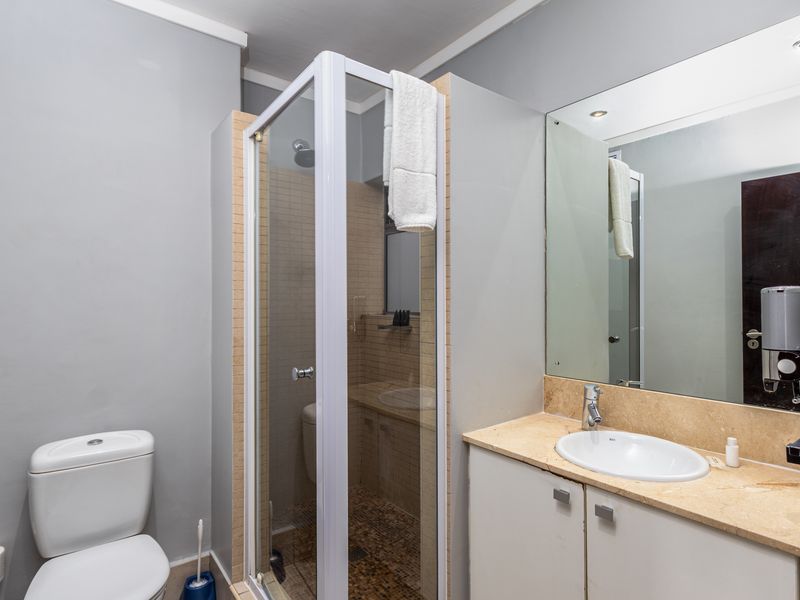 A functional bathroom featuring a glass shower enclosure, a vanity with a stone countertop, and a wall-mounted mirror.