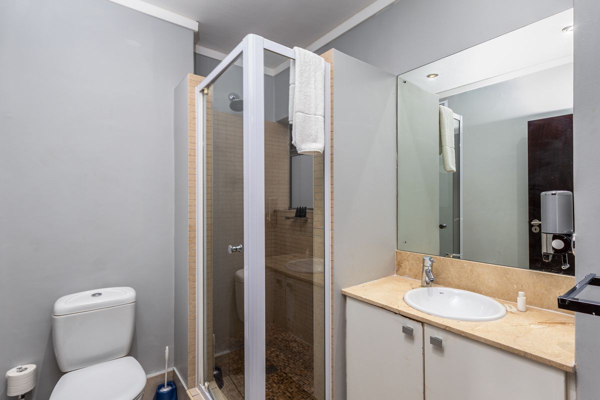 A functional bathroom featuring a glass shower enclosure, a vanity with a stone countertop, and a wall-mounted mirror.