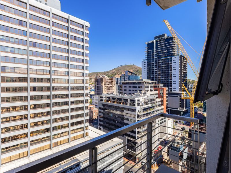 An elevated urban view from a balcony overlooking surrounding high-rise buildings and city infrastructure.