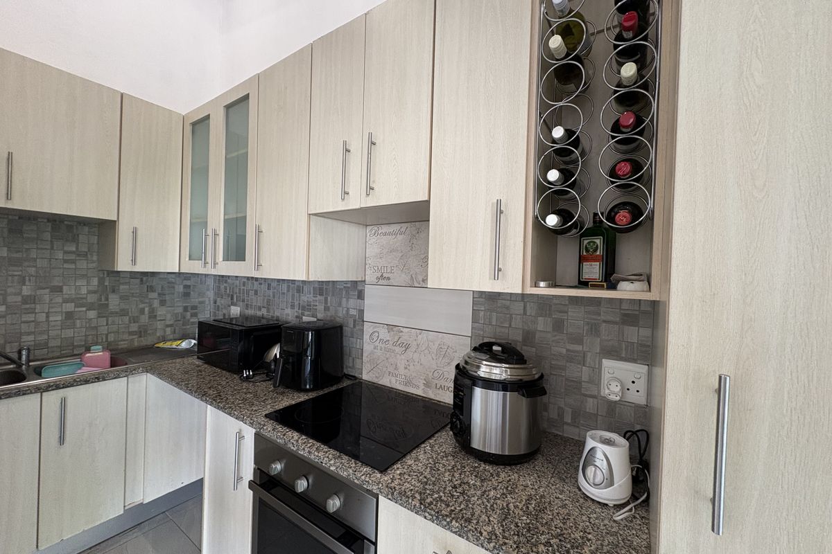 A functional kitchen featuring light wood-grain cabinetry, granite countertops, a mosaic tile backsplash, a built-in oven, and a glass ceramic hob.