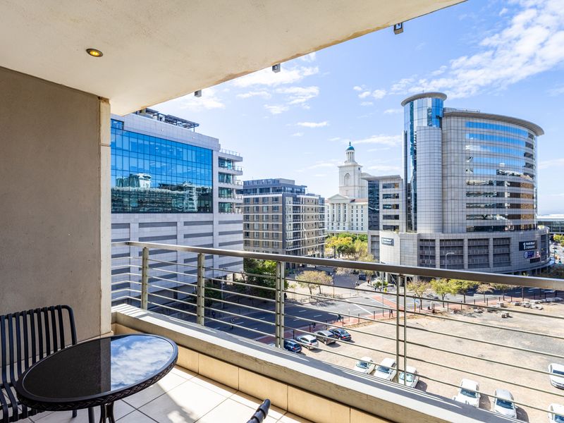 A covered balcony featuring tiled flooring, recessed lighting, and a metal railing, offering an expansive urban city view.