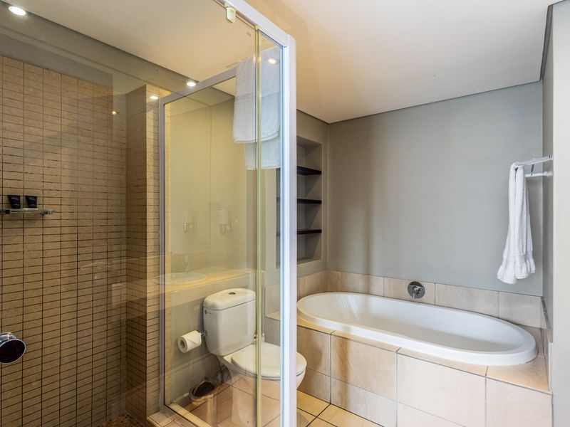 Modern bathroom featuring a glass-enclosed shower, a built-in bathtub with tiled surround, and recessed shelving for storage.