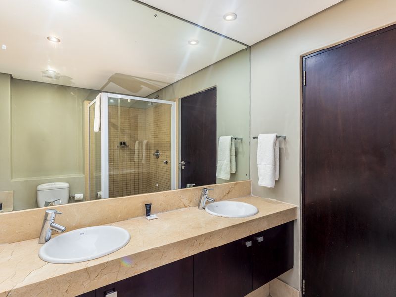 Modern bathroom featuring a double vanity with stone countertop, large wall mirror, and a separate shower enclosure.