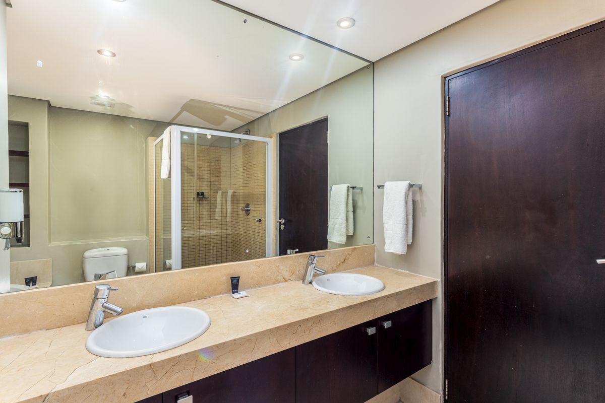 Modern bathroom featuring a double vanity with stone countertop, large wall mirror, and a separate shower enclosure.