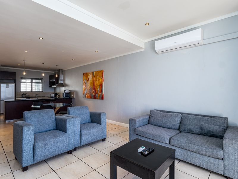 Open-plan living area featuring tiled flooring, recessed lighting, and a split-system air conditioner, seamlessly connected to a functional kitchen space.