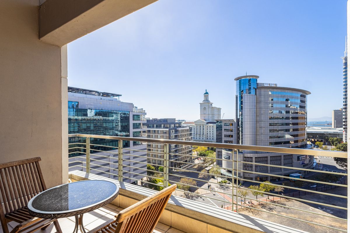 A private balcony featuring a metal balustrade and tiled flooring, offering expansive views of the surrounding city skyline.