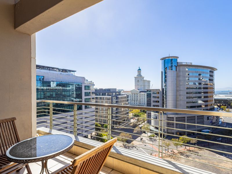 A private balcony featuring a metal balustrade and tiled flooring, offering expansive views of the surrounding city skyline.