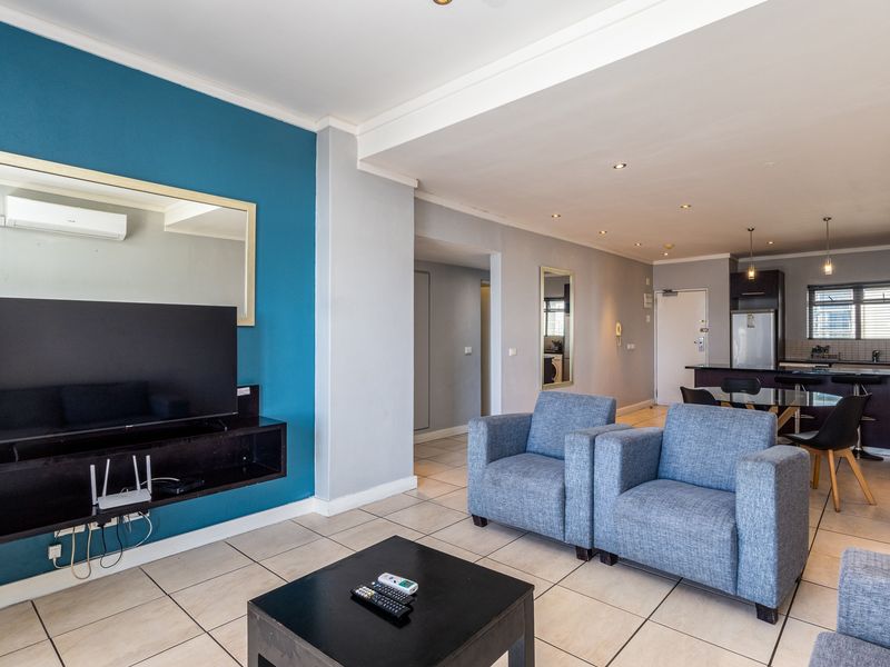 Open-plan living and kitchen area featuring tiled floors, recessed lighting, and a modern kitchen layout with a breakfast island.