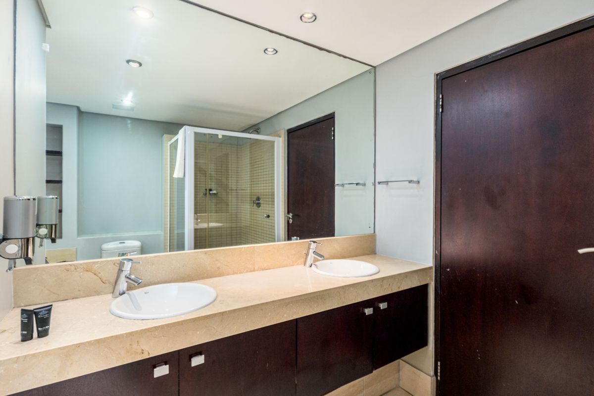 A modern bathroom featuring a double vanity with stone countertops, under-mount sinks, a large wall mirror, and a separate shower enclosure.