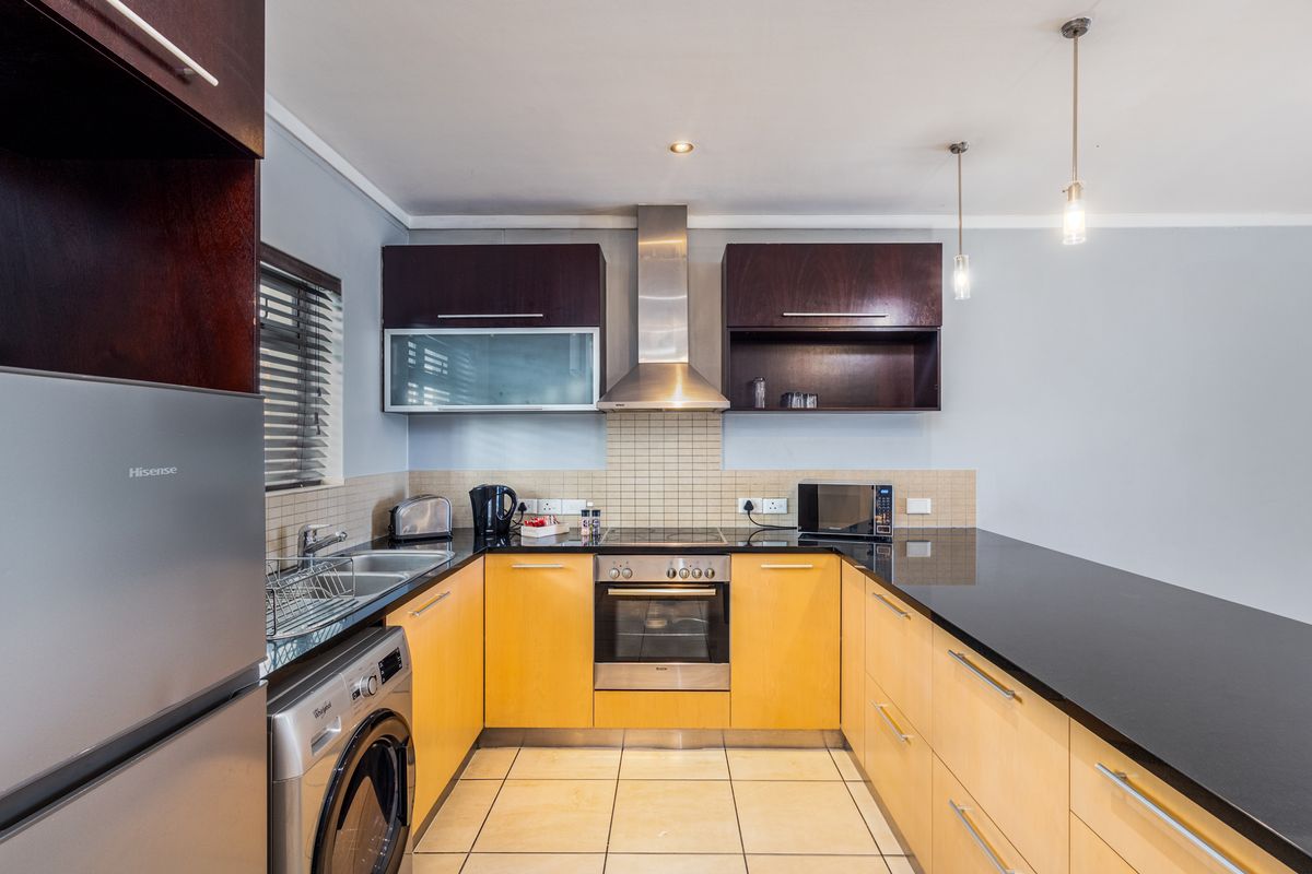 Modern kitchen featuring light wood cabinetry, dark granite countertops, stainless steel appliances, tiled backsplash, and functional layout with integrated sink and hob.
