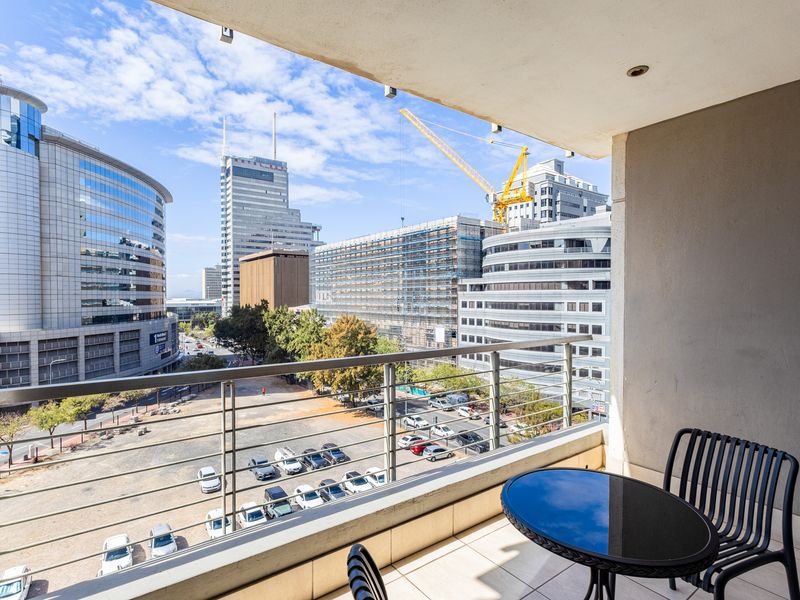 A covered balcony featuring tiled flooring, a metal balustrade, and recessed ceiling lighting, offering an expansive urban city view.