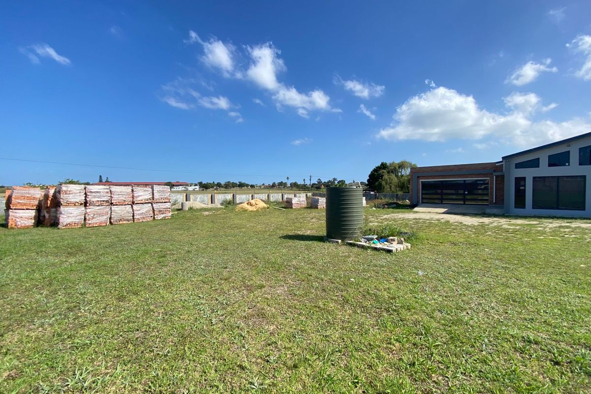 A view of the residential vacant land featuring a water tank, stacked construction materials, and a partial view of an adjacent building structure.