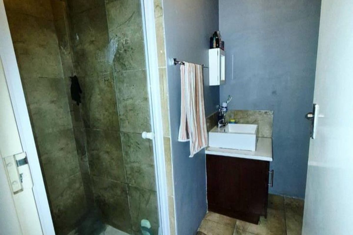 A compact bathroom featuring a glass-enclosed shower, a modern vessel sink vanity, and tiled flooring.