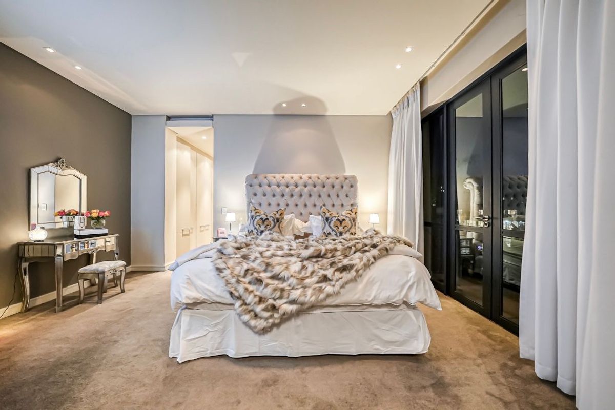 Spacious bedroom featuring plush carpeting, recessed ceiling lighting, and large glass sliding doors leading to an outdoor area, complemented by a walk-in closet.