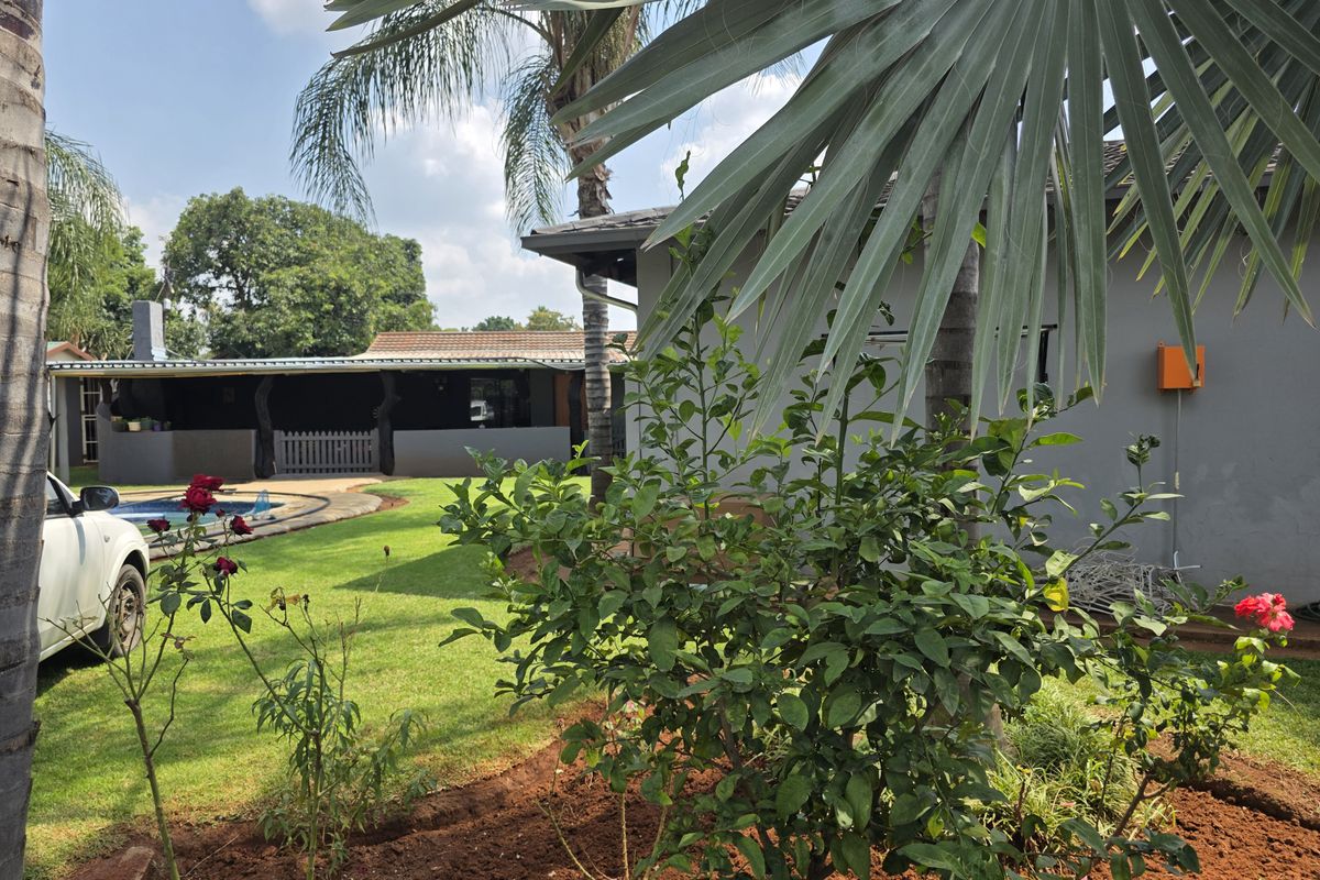 A view of the rear garden featuring a swimming pool, a covered patio area, and established landscaping.