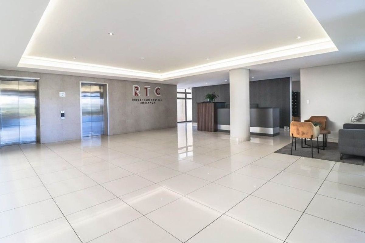 Modern apartment building lobby featuring polished tile flooring, recessed ceiling lighting, and dual elevator access.