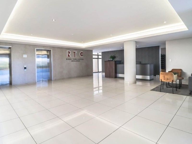 Modern apartment building lobby featuring polished tile flooring, recessed ceiling lighting, and dual elevator access.