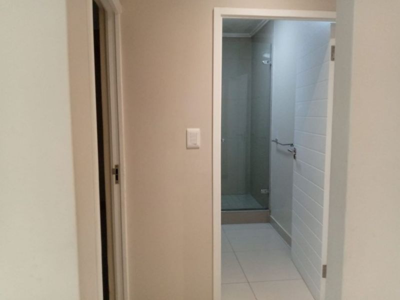 A view from a hallway looking into a modern bathroom featuring a glass-enclosed shower and tiled flooring.