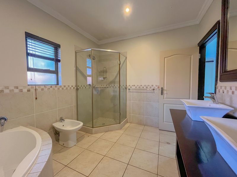 Spacious bathroom featuring a corner shower, built-in bathtub, bidet, and a double vanity with modern vessel sinks.