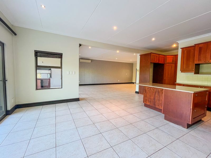 Spacious open-plan living and kitchen area featuring tiled flooring, recessed lighting, and traditional wooden cabinetry, offering a versatile layout for modern living.