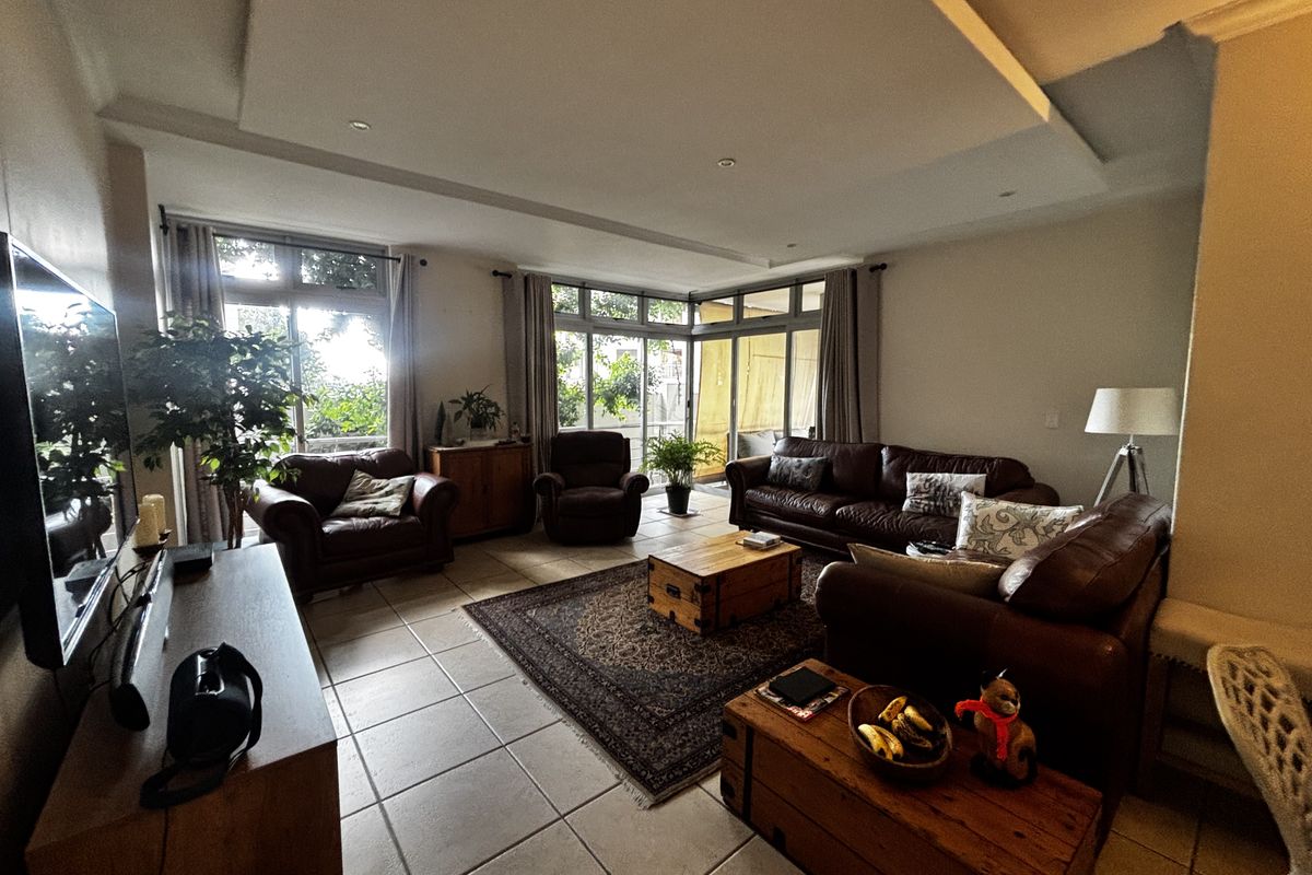 Spacious living room featuring large windows, tiled flooring, and a recessed ceiling design, offering ample natural light and access to an outdoor area.