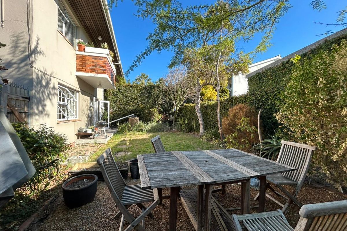 A private rear garden area featuring a gravel patio space, lawn, and established perimeter hedging, providing a quiet outdoor retreat.
