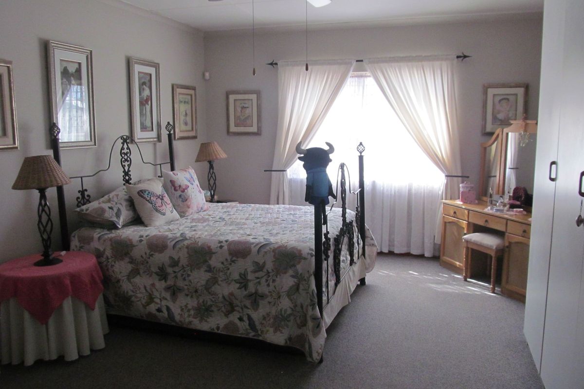A spacious bedroom featuring neutral carpeting, a ceiling fan, and built-in wardrobe storage, offering a comfortable and functional living space.