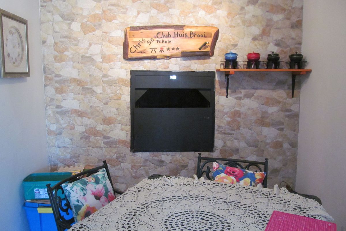 Indoor entertainment area featuring a built-in braai fireplace with a decorative stone-cladding feature wall.