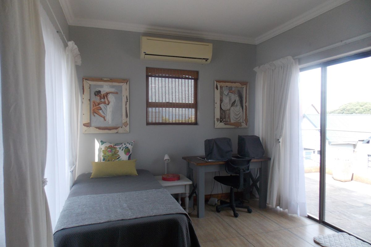 A bedroom featuring tiled flooring, a wall-mounted air conditioning unit, and sliding glass doors providing access to an outdoor balcony area.