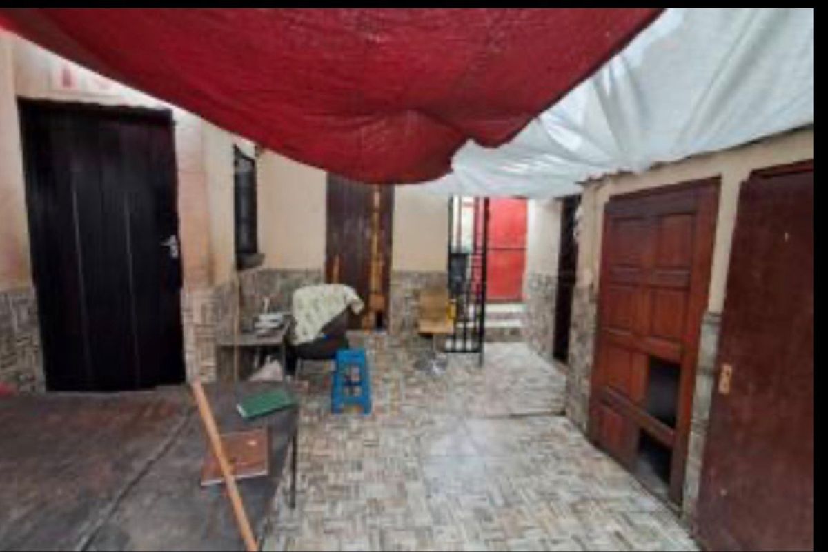 An outdoor courtyard or patio area featuring tiled flooring, multiple access doors, and a temporary fabric shade structure.