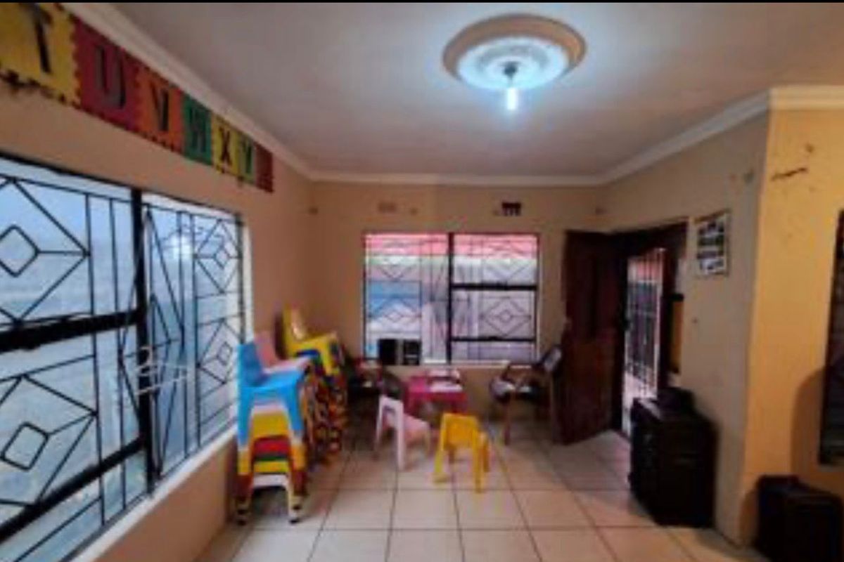 A living area featuring tiled flooring, security bars on windows, and a ceiling rose, providing a functional space with potential for cosmetic updates.